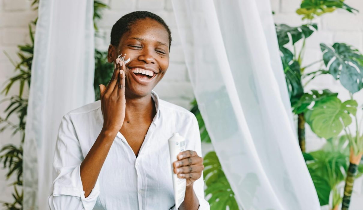Woman Applying Face Cream and Smiling